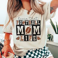 Livin That Football Mom Life Shirt, Sports Mom Shirts,Mom's Football T-Shirt,Game Day T-shirt,Football Season Shirt,Football Mom Graphic Tee ---How To Order --- 1-) Please, check and review all photos 2-) Choose your t-shirt size and color 3-) Click add to cart. You can go back to add more product 4-)Click "Proceed to check out" 5-)When you check out, you can add a note to seller for any request ---Production and Shipping--- * High quality and super soft, comfortable shirt. Made with top-of-the- Football Season Letter Print T-shirt, Mom Graphic Tees, Sports Mom Shirts, Football Mom Shirts, Shirt Football, Football T Shirt, Mom Life Shirt, Game Day Shirts, Mama Shirts