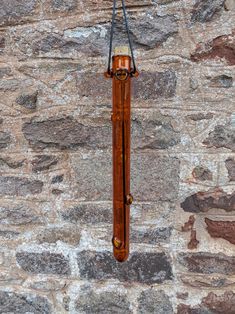 a clock hanging from the side of a stone wall next to a brick wall with a wire attached