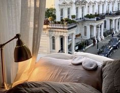 a bed sitting in front of a window next to a tall white building with lots of windows