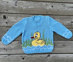 a blue sweater with a duck in the grass on it