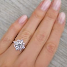 a woman's hand with a diamond ring on top of her finger, showing the center stone