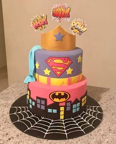 a multi layer cake decorated with batman, superman and spider - man symbols on top