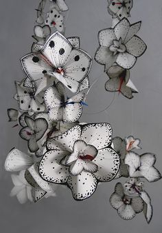 a group of white flowers hanging from the ceiling in a room with grey walls and flooring