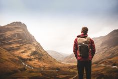 a man standing on top of a mountain looking at the valley