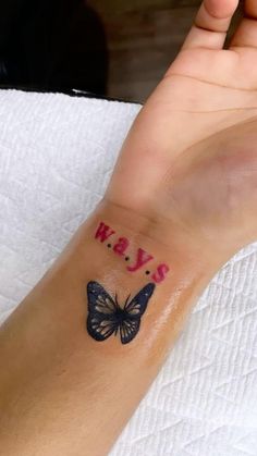 a person's arm with a butterfly tattoo on it and the word may written in pink ink