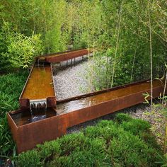 an outdoor water feature in the middle of some bushes and trees, surrounded by tall grass