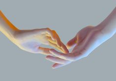 two hands reaching out towards each other on a gray background with light coming from above