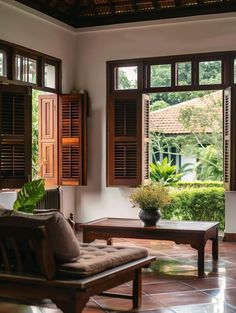 a living room filled with furniture and windows covered in wooden shutters next to a tiled floor