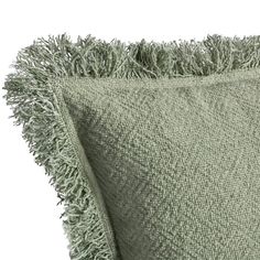 a green throw pillow with fringes on it