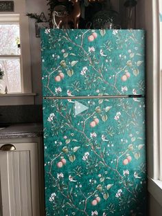 a green refrigerator covered in flowers and birds