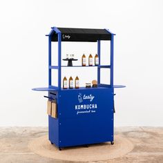 a blue cart sitting on top of a wooden floor next to a wall with bottles in it