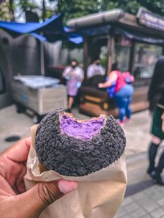 a person holding up a donut with purple frosting