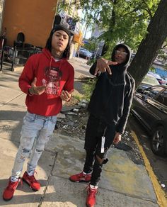 two young men standing next to each other on a sidewalk