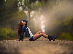 a woman sitting on the ground with her legs crossed and head tilted to the side