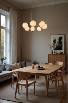 a dining room table and chairs with lights hanging from the ceiling