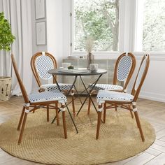 a round table with four chairs and a potted plant in the corner next to it