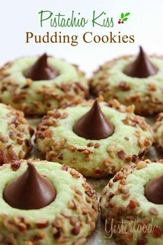 some cookies with chocolate and nuts on top are sitting on a white plate, surrounded by the words pistachio kiss pudding cookies