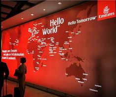 people are standing in front of a red wall with words on it that read hello world