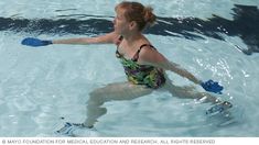 a woman in a swim suit and blue gloves is playing in the water with a frisbee