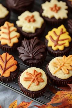 cupcakes decorated with leaves and frosting on a cooling rack in the fall