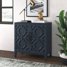 a black cabinet with a lamp on top next to a potted plant