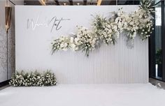 the wedding backdrop is decorated with white flowers and greenery