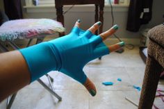 a woman's hand with blue gloves on it in the middle of a room