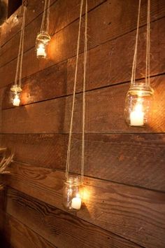 mason jar lights hanging from the side of a wooden wall