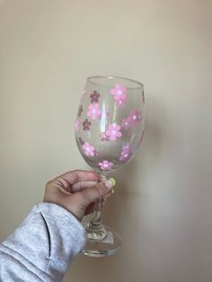 a hand holding a wine glass with pink flowers on it