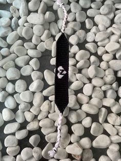 a black and white beaded tie with an anchor on it sitting on some rocks