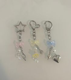 four key chains with charms attached to them on a white surface, one has a heart and the other has a star