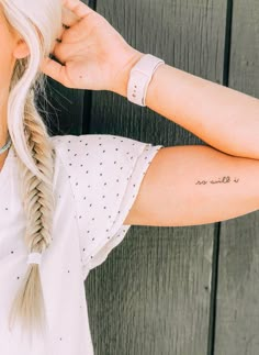 a woman with a tattoo on her left arm and right arm behind her head, wearing a white t - shirt