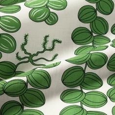 a green and white fabric with small leaves on it's side, as well as an image of a plant