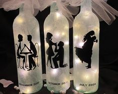 three lighted bottles with silhouettes of people on them, sitting next to each other