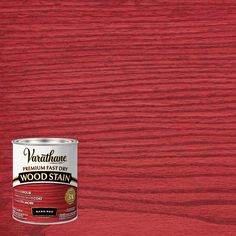 a can of wood stain sitting on top of a wooden floor next to a red wall