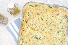 a casserole dish with cheese and vegetables in it on a towel next to some condiments