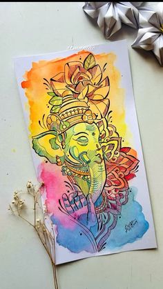 an elephant with a crown on it's head sitting next to some flowers and paper