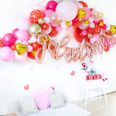 the balloon wall is decorated with pink, red and gold balloons that spell out love