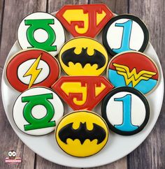 decorated cookies are arranged in the shape of batman and superman logos on a white plate