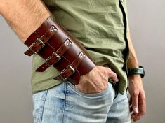 a man wearing a leather wristband with multiple buckles on his left arm and the other hand