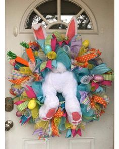 a wreath with an easter bunny on it is hanging on the front door to give as a decoration