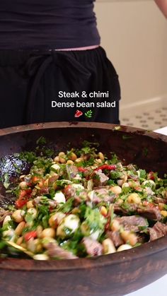 a woman standing in front of a pan filled with food on top of a table