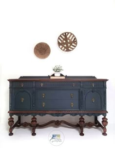 an old dresser with two decorative plates on the wall