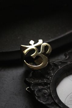 Cool Ohm Sign Ring (version two) original made and designed by Defy Own unique design of Ohm, spiritual meaning of the sacred sound. This version shows detail of the ohm sign in three dimensional. -The ring size is between 7 - 10 US. **Please choose options below.** - The ring dimensions are ; approx. 2.5 x 2.5 x 2.5 cm. **Shipping to World Wide** - Please allow us to prepare the item and parcel between 3-5 working days. For Brass / Silver plated / Gold plated (*Between 5-7 working days For Ster Symbolic Brass Promise Rings, Brass Promise Rings, Spiritual Rings As Festival Gifts, Spiritual Rings For Festivals Gift, Spiritual Promise Rings, Nickel-free Brass Symbolic Ring, Ohm Ring, Ohm Sign, Skull Jewelry