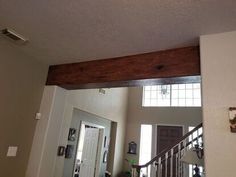 the entry way to a house with a wooden beam on it's ceiling and an open door