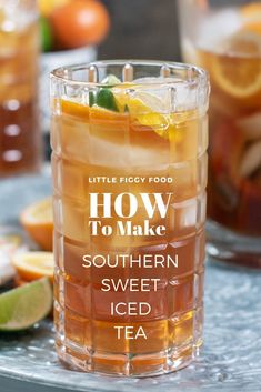 a close up of a drink in a glass on a table with oranges and limes