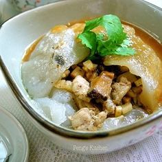 a bowl filled with food sitting on top of a white table covered in sauce and garnish