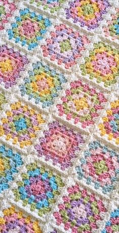 a multicolored crocheted blanket with squares and flowers on the bottom half