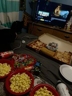 some food is laying out on the bed in front of a flat screen t v