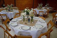 the table is set with white flowers and place settings